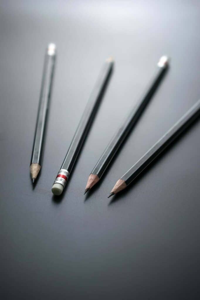 corma- A group of pencils on a black surface.